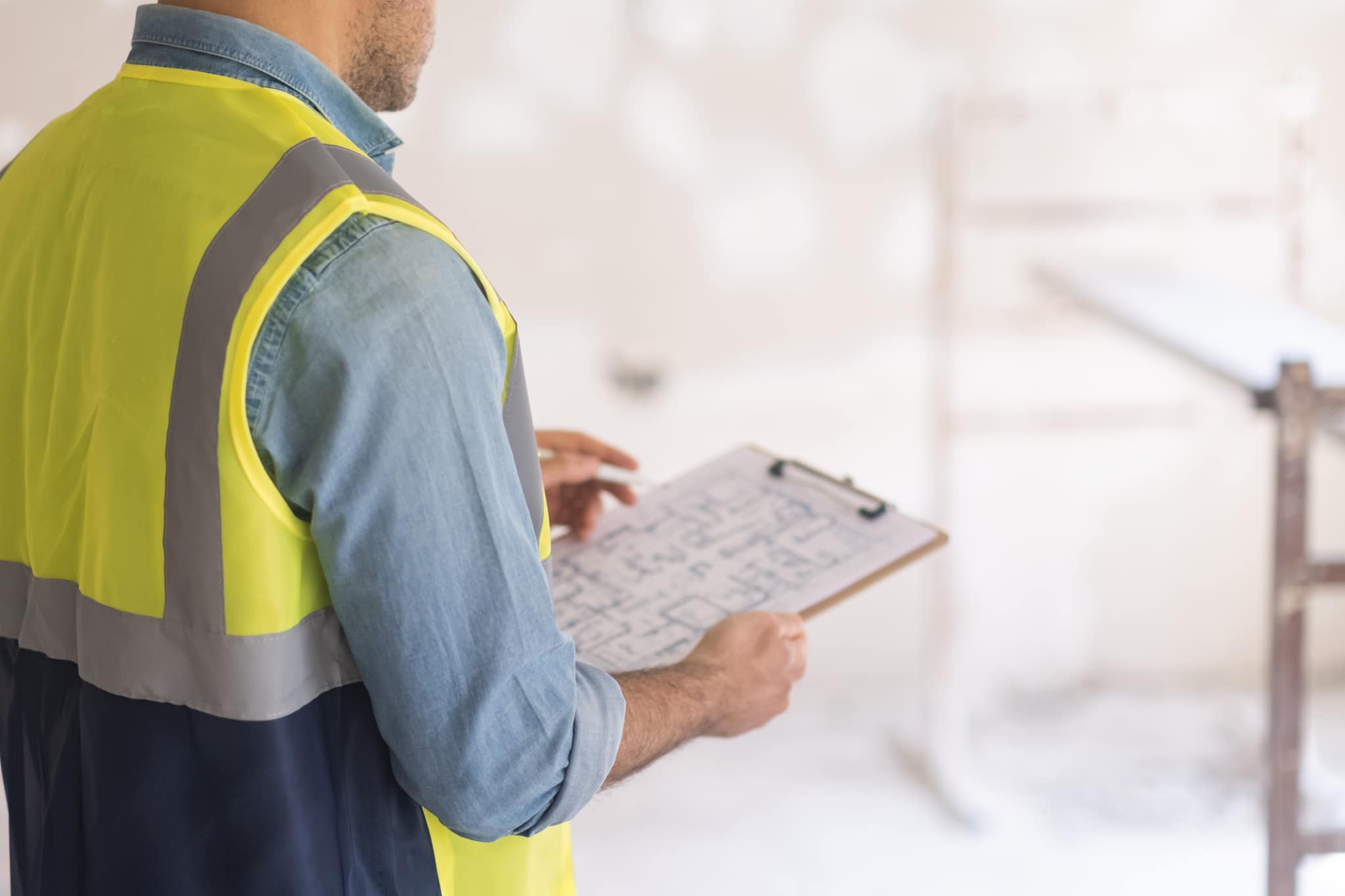 Foreman in vest checking drawing plan of big house holding clipboard in hands